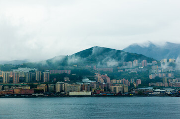 Naklejka premium View from the sea to the bay in the city of Genoa Italy. A city by the sea and mountains nearby in the fog.