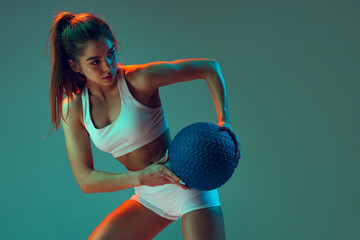 Portrait of sportive woman workout, doing exercises with sports equipment isolated on green studio...
