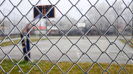 Close-up chain link fence with a view across the basketball playing area.