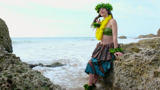Exotic woman dressed in the typical Polynesian costume posing relaxed on the shore of the beach