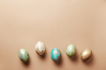 Creative multi-colored eggs on a brown background view from above. Stylish design for Easter day with space for text.