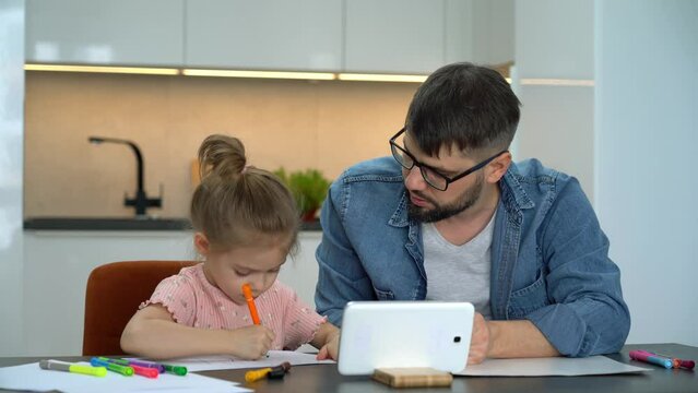 Father and little girl learn to draw watching drawing lesson on internet. Online education concept. Video tutorial, drawing training.
