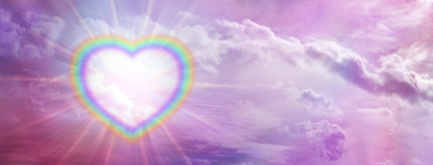 Rainbow love heart romantic  sky message banner - a large empty multicoloured border illuminated  heart creating a frame on left side of pink sky background with copy space for messages
