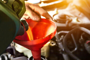A technician man pouring the engine oil in a car service.