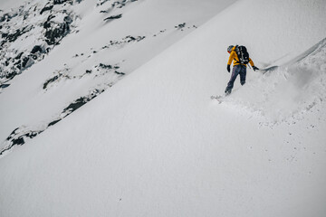 Splitboarder or a freerider riding a snowboard in deep powder snow. Exreme winter sport, freeride...