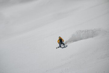Splitboarder or a freerider riding a snowboard in deep powder snow. Exreme winter sport, freeride in high mountains. Powder snow riding on splitboard.