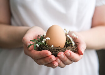 Nest with an egg in female hands. Natural eco-friendly Easter decor. Easter decor in rustic style