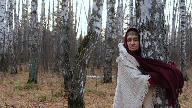 Elderly woman walking in a birch forest