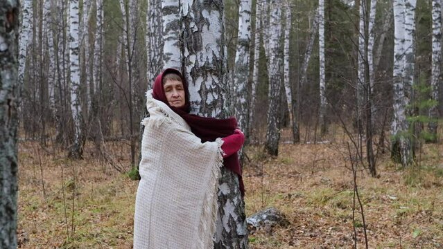 Elderly woman walking in a birch forest