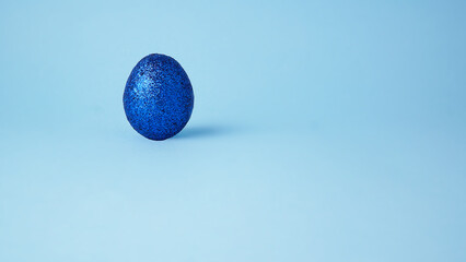 Blue glitter Easter egg. 
Light blue background. Clear minimal luxury concept. 
Space for text.