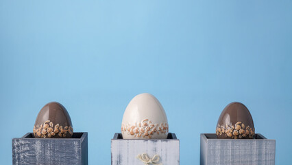 Easter arrangement. Beautiful Easter eggs in small decorative wooden drawers. Elegant Easter minimalism on a blue background.