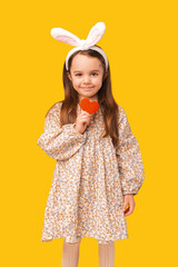 A little girl wearing easter ears and holding a little red heart.