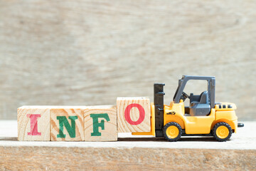 Toy forklift hold letter block o to complete word info on wood background