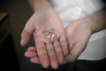 Earrings on woman's ears on dark background, hands, fingers