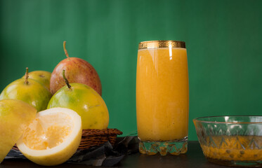 Passion fruit in a basket and its juice on a black wooden table with green background 