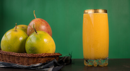 Passion fruit in a basket and its juice on a black wooden table with green background 