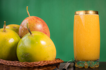 Passion fruit in a basket and its juice on a black wooden table with green background 
