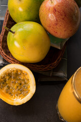 Passion fruit in a basket and its juice on a black wooden table 
