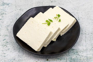 Sliced Feta cheese with herbs on stone background. Close-up breakfast cheese