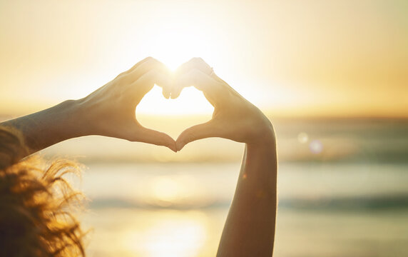 Gotta love summer. Closeup shot of an unidentifiable woman forming a heart shape with her hands at the beach.