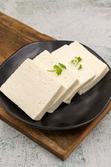 Sliced Feta cheese with herbs on stone background. Close-up breakfast cheese
