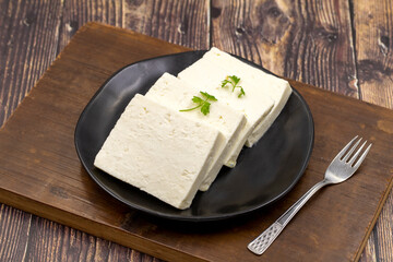 Sliced Feta cheese with herbs on wooden background. Close-up breakfast cheese