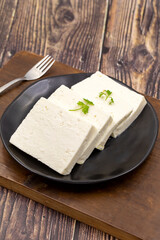 Sliced Feta cheese with herbs on wooden background. Close-up breakfast cheese