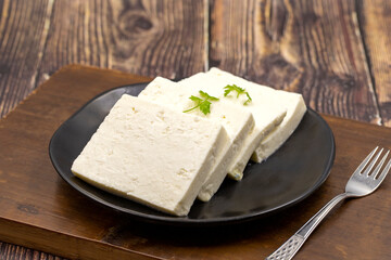 Sliced Feta cheese with herbs on wooden background. Close-up breakfast cheese