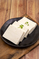 Sliced Feta cheese with herbs on wooden background. Close-up breakfast cheese