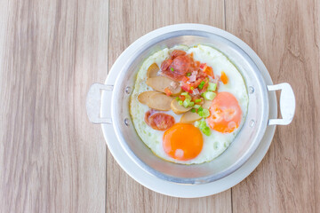 Fried egg, Chinese pork sausages, chopped chicken sausage were served in a pan as a breakfast meal in the morning in Thai style.
