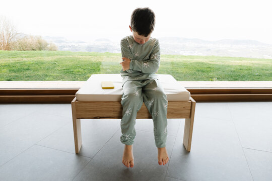Boy in pajama sitting on pouf doing tantrum