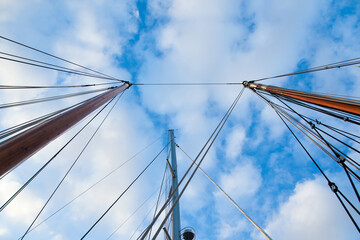 Masts of sailing yachts without sails with anchoring ropes. View from below.