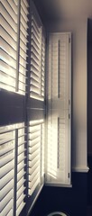 Vertical image of light shining through window with plantation shutters