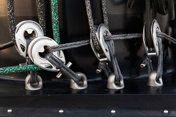 Part of the mast and hull of a sailing yacht, with multi-colored ropes, rollers and hinges for...