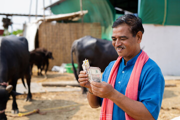 smiling milk dairy farmer counting money at farm - conept of successful business, profit, financial and banking - obrazy, fototapety, plakaty