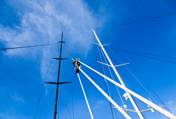 Fototapeta premium Masts of sailing yachts without sails with anchoring ropes. View from below.
