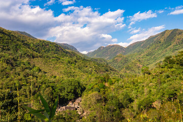 mountain valley covered with green forests and bright blue sky at afternoon from flat angle