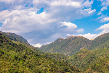 mountain valley covered with green forests and bright blue sky at afternoon from flat angle