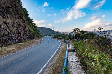 isolated mountain tarmac curvy road with bright blue sky at evening from flat angle