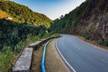isolated mountain tarmac curvy road with bright blue sky at evening from flat angle