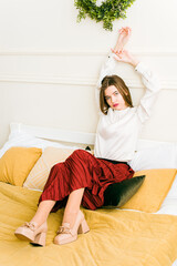 Portrait of fashionable women in red skirt, white blouse and stylish beige high-heeled shoes with a...