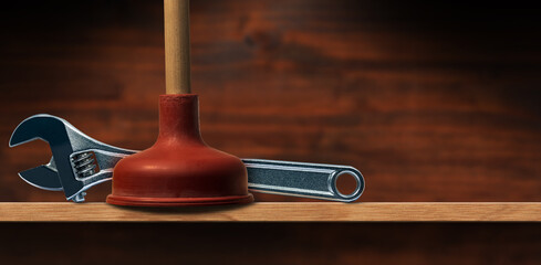 Close-up of a red rubber plunger with wooden handle and a modern stainless steel adjustable wrench...