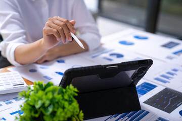 Businesswoman uses a tablet for a marketing project while analyzing company turnover using a laptop...