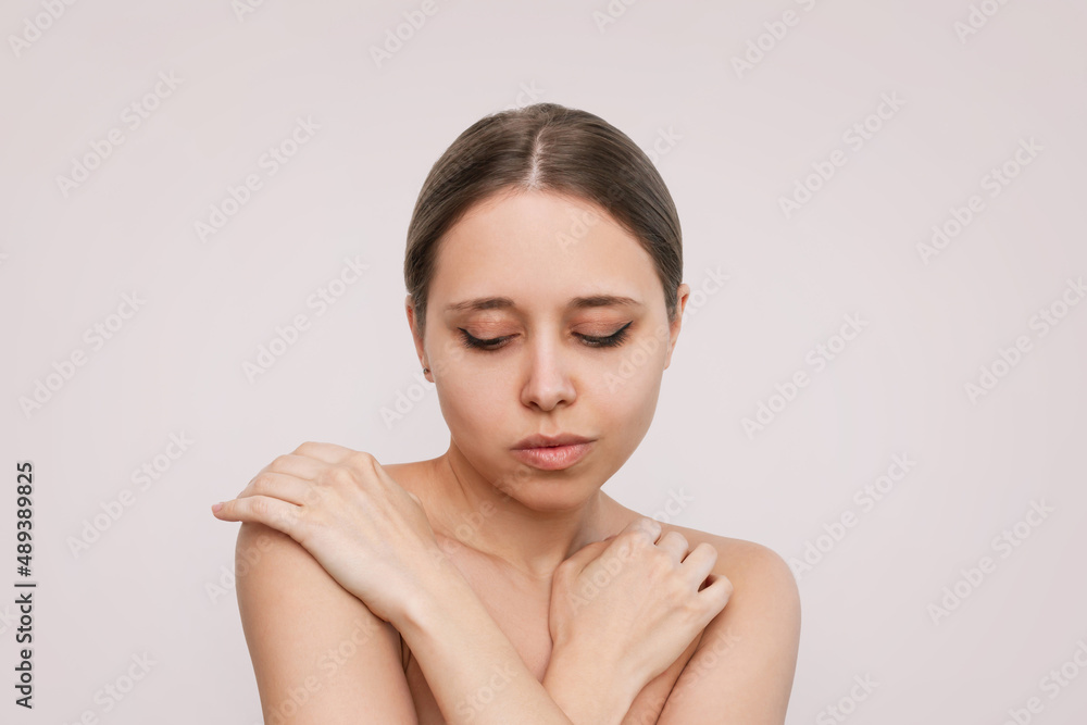 Wall mural portrait of a young attractive caucasian blonde woman with makeup touching the skin of her body isol