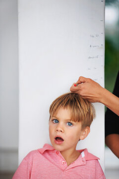 Wow, youve really grown. Portrait of a shocked young boy having his height measured by his mother on the kitchen wall.