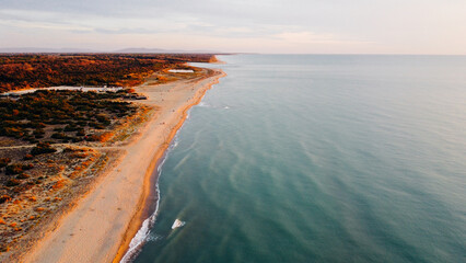 Aerial view of coastline and fall vegetation in Tuscany; Italy. Bird's eye view of sandy shore and Ligurian sea at sunset. Drone photography.