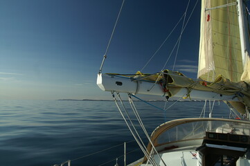jacht z żółtym żaglem płynący po spokojnym morzu w słoneczny dzień - obrazy, fototapety, plakaty