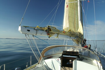 jacht z żółtym żaglem płynący po spokojnym morzu w słoneczny dzień - 489394445