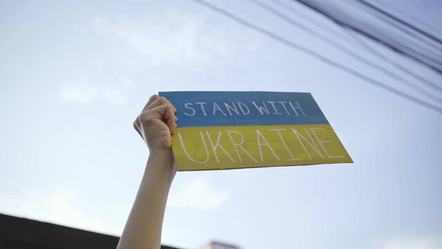 Demonstrator holding "Stand with Ukraine" placard