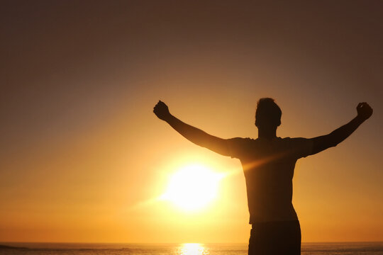 Breaking Free From The Rut. Silhouette Of A Man With His Arms Outstretched With The Sunset In Front Of Him.